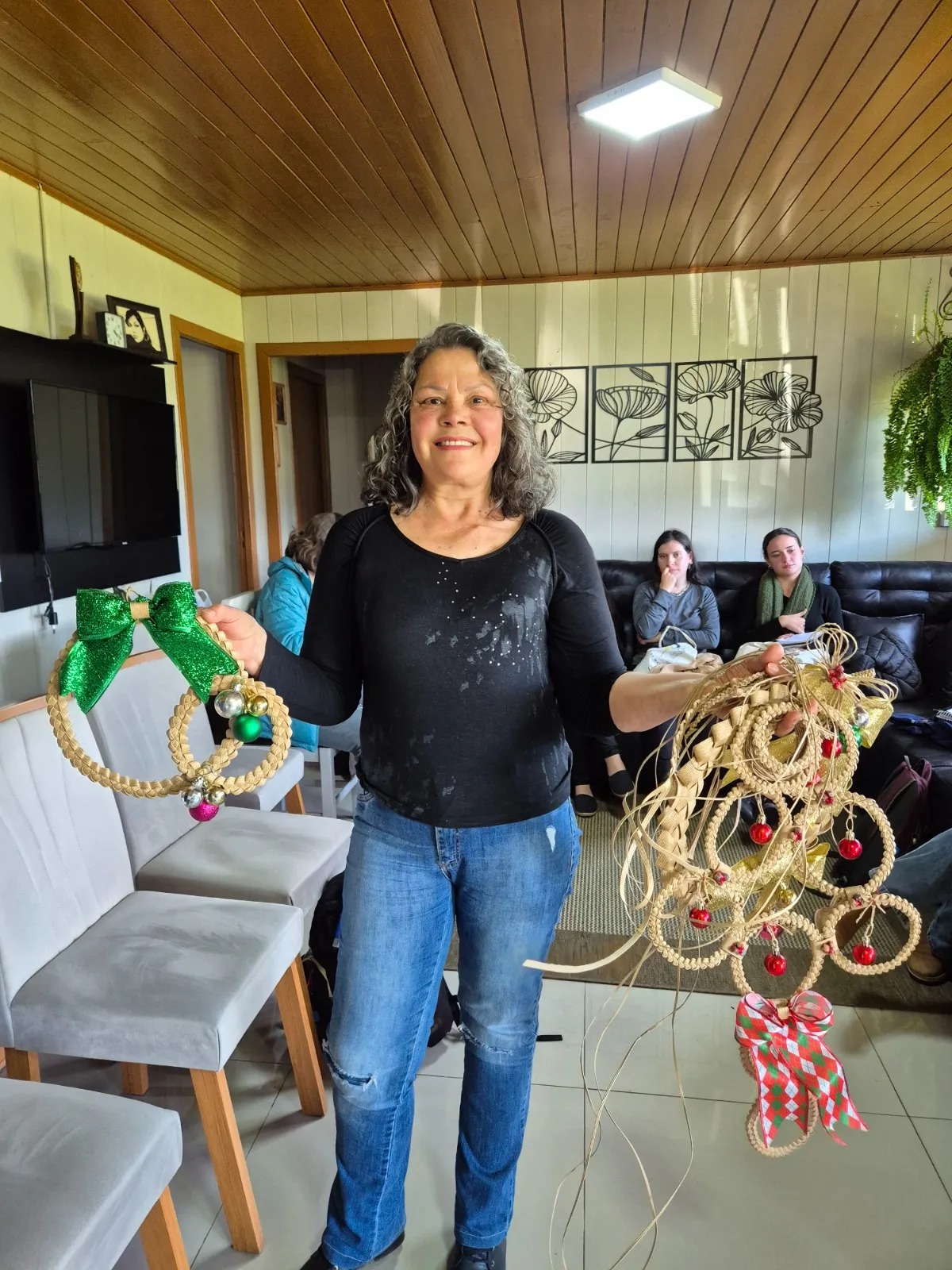 Uma das participantes sorri e exibe suas produções artesanais